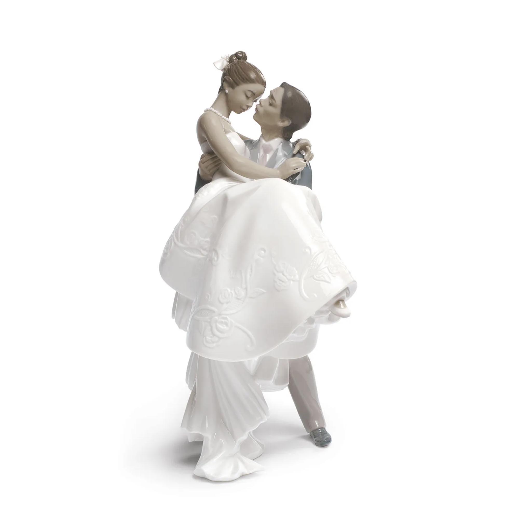 The Happiest Day Couple Figurine Gloss white porcelain figurine of a couple, where he lifts her and her carefully embroidered dress in his arms.